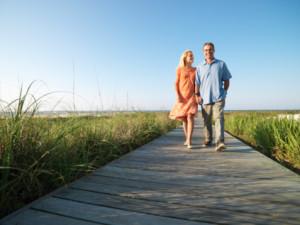 Couple walking on boardwalk through grass