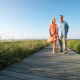 Couple walking on boardwalk through grass