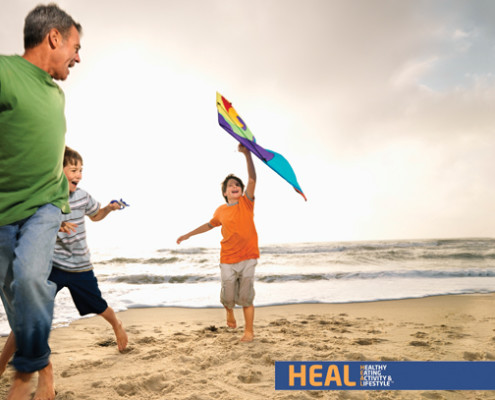 Dad playing with sons on the beach