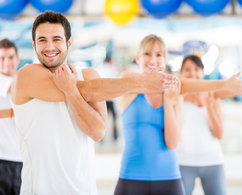 Man stretching at front of gym class