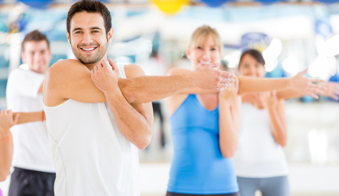 Man stretching at front of gym class