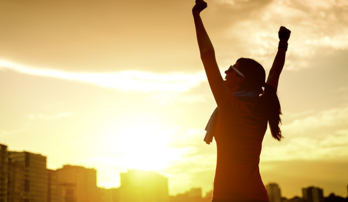 Woman with arms in air sunset