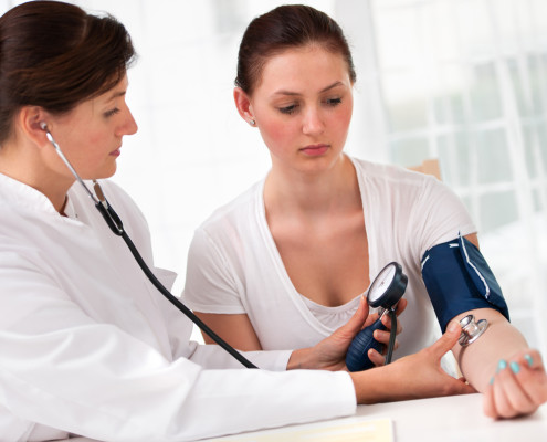 Doctor taking woman's blood pressure