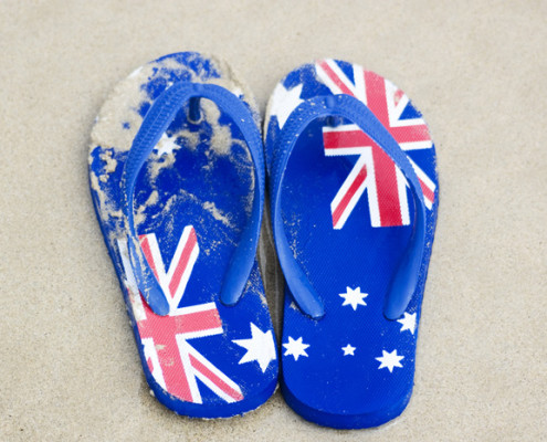 Thongs with Australian flag pattern on sand at beach