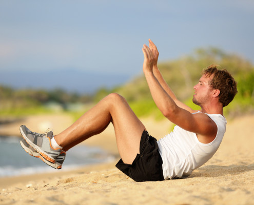 Man doing crunches on beach