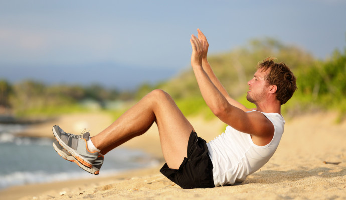 Man doing crunches on beach