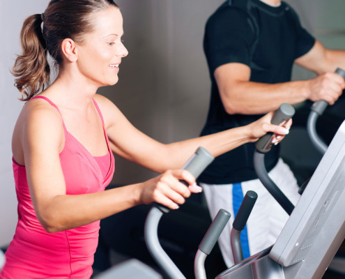 Woman and man training side by side on exercise equipment