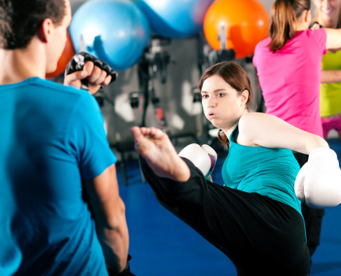 Woman kick-boxing in gym with male partner