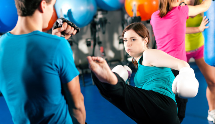 Woman kick-boxing in gym with male partner